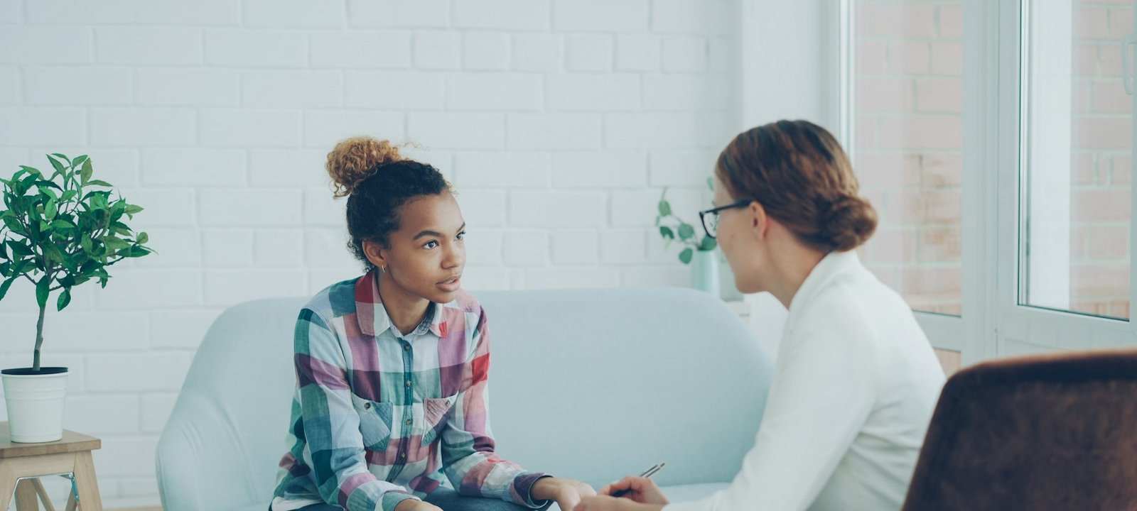 A professional listening and taking notes while a young woman talks