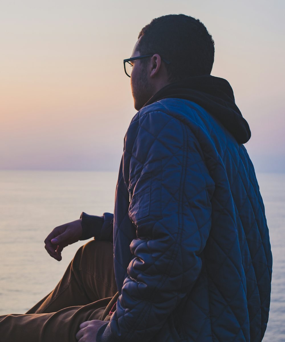 A man sitting quietly by the sea at dusk, lost in thought