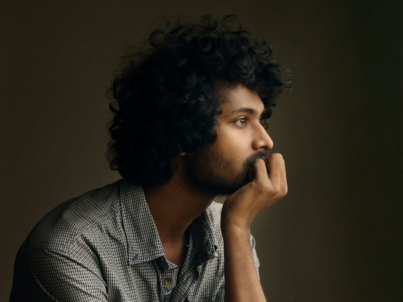 A young man resting his chin on his hand, deep in thought