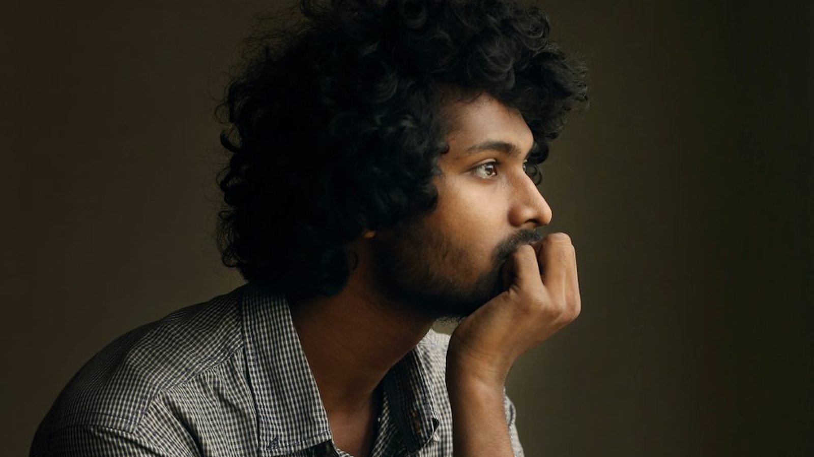 A young man resting his chin on his hand, deep in thought
