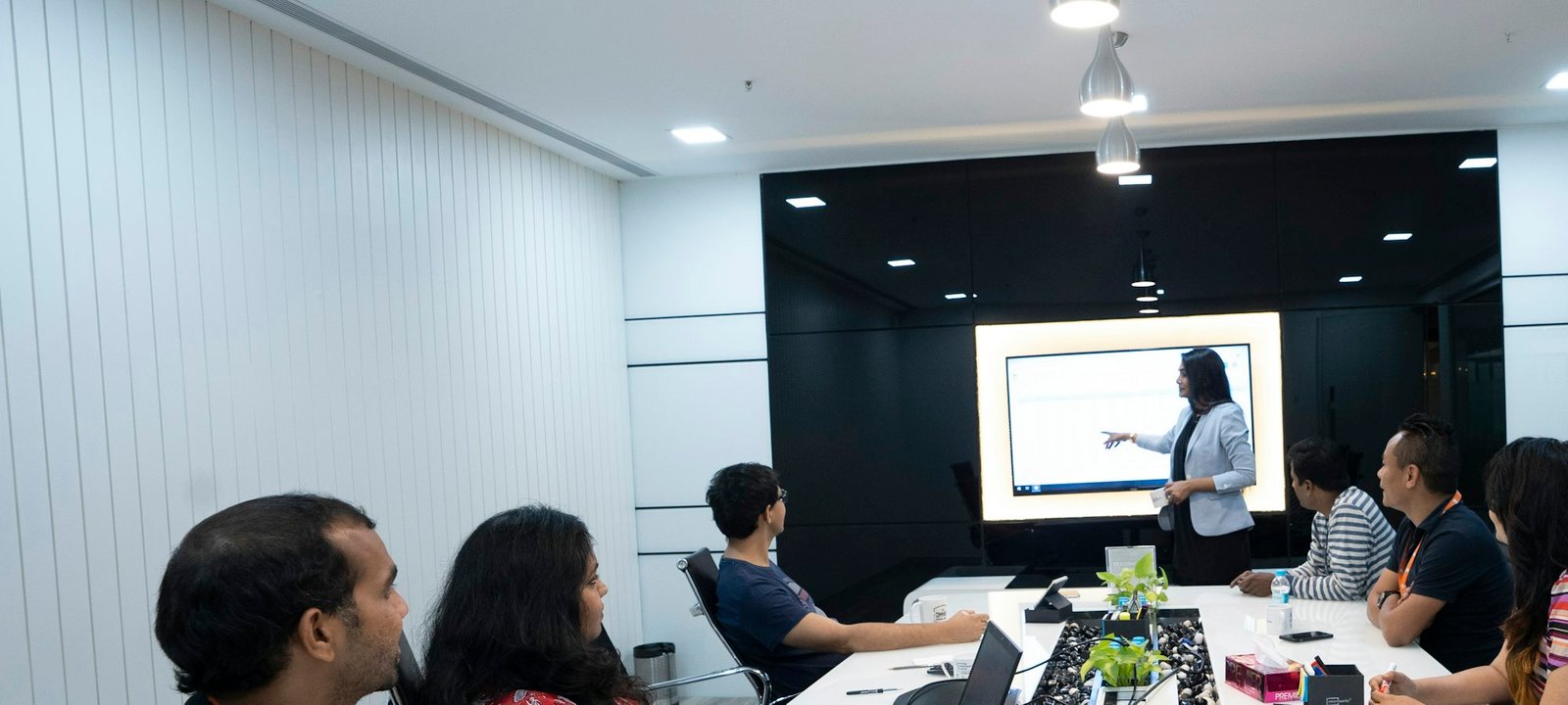A team in a meeting room listening to a colleague presenting