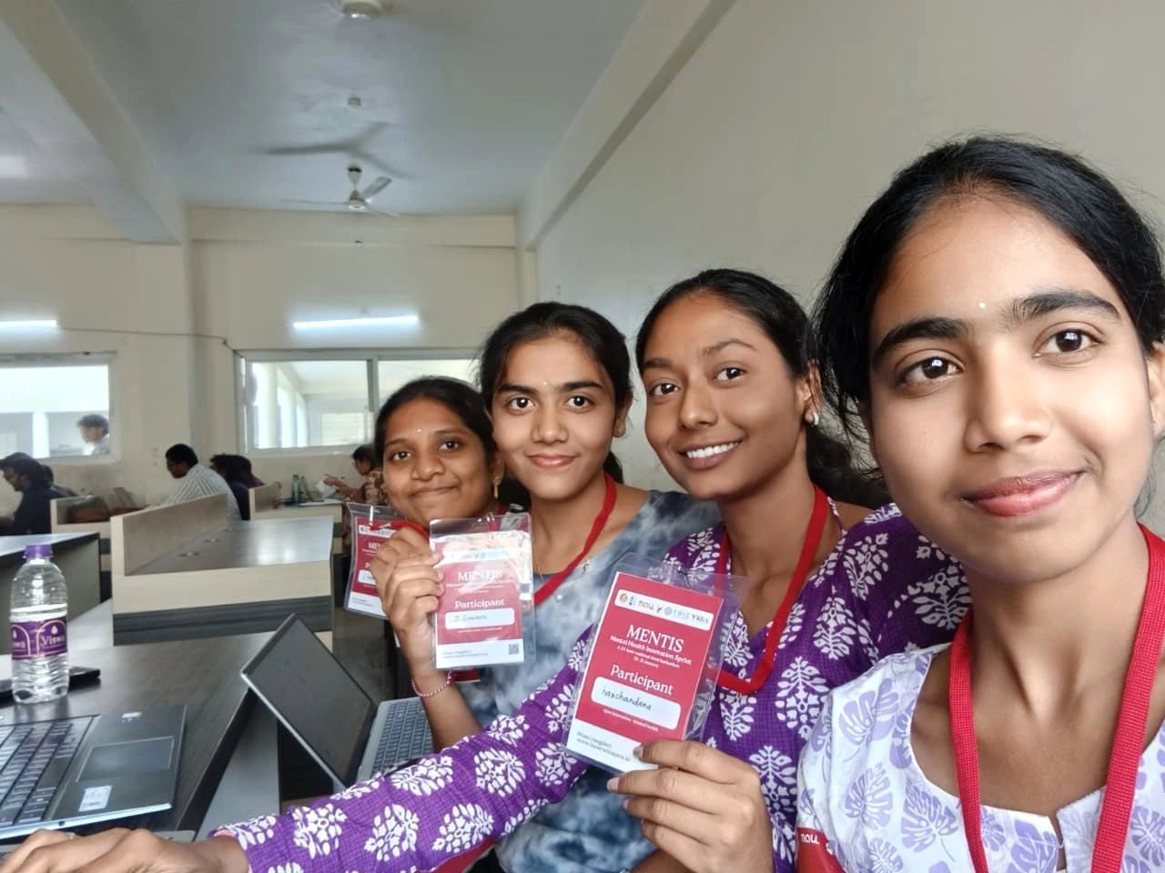 Four student participants smiling and holding their MENTIS participant badges during the hackathon at Vaagdevi College of Engineering, Warangal