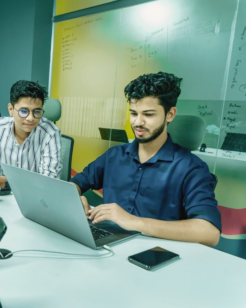 Two young interns working on laptops in a bright startup office