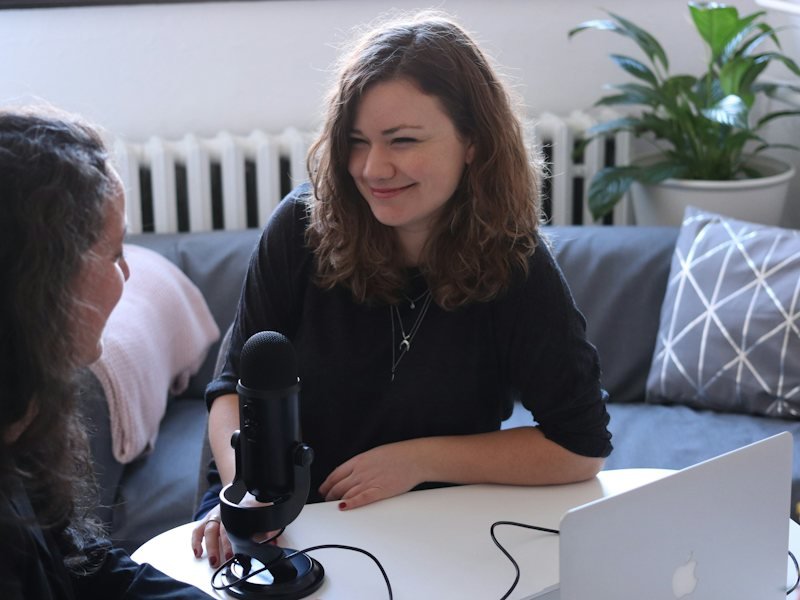 Two women talking across a table with a microphone between them