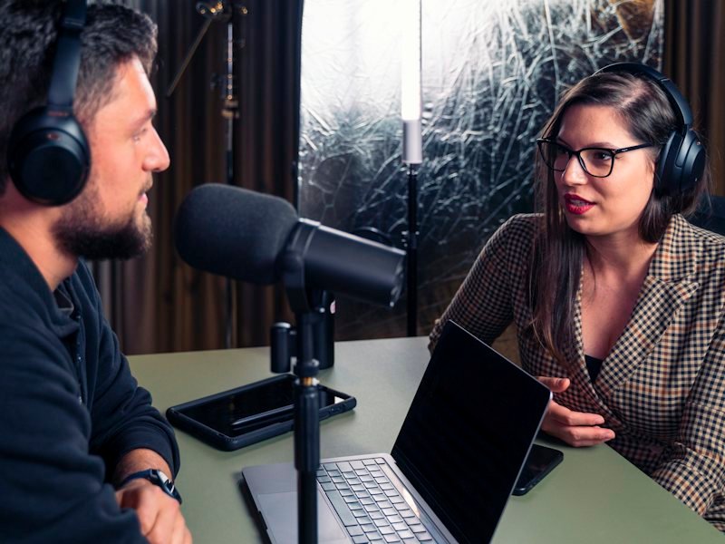 A man and a woman in headphones recording an interview