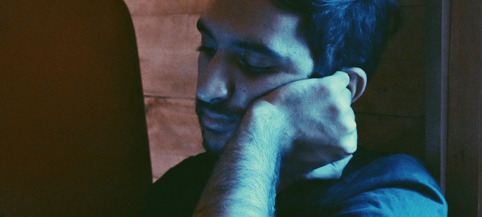 A young man resting his head on his hand, deep in thought