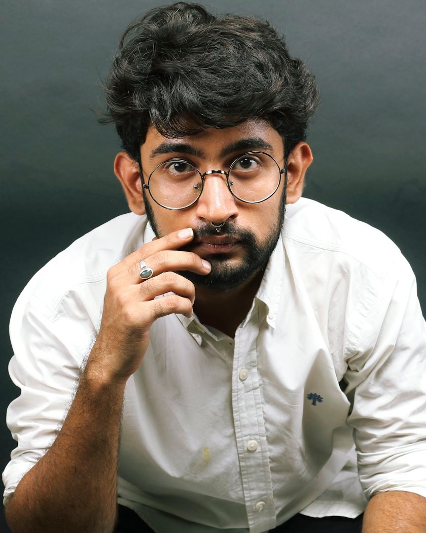 A young man in glasses, thinking with his hand on his chin