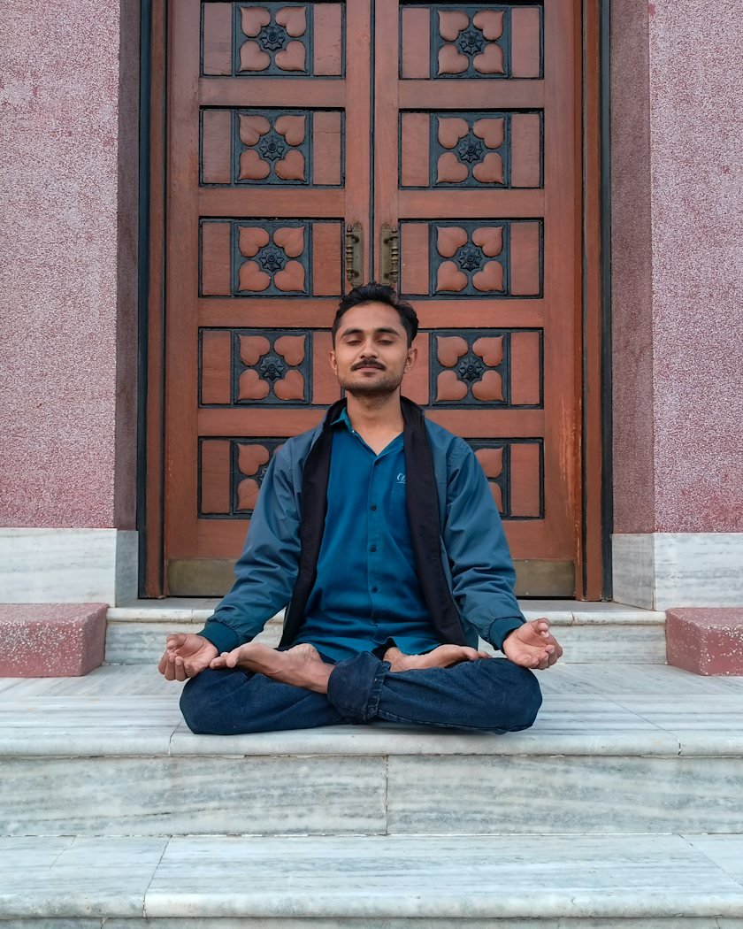 A man meditating calmly on the steps outside a building