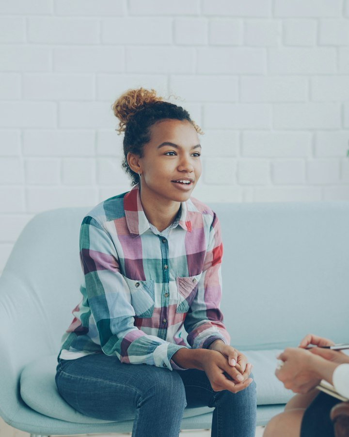 A young woman talking openly with a mental health professional who is taking notes