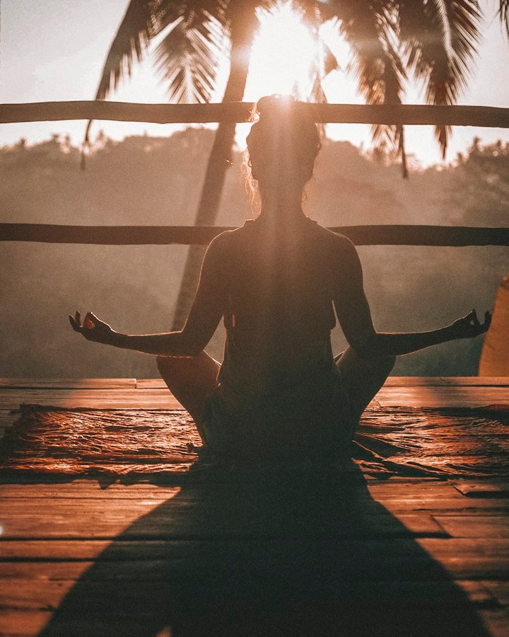 A person meditating cross-legged at sunrise