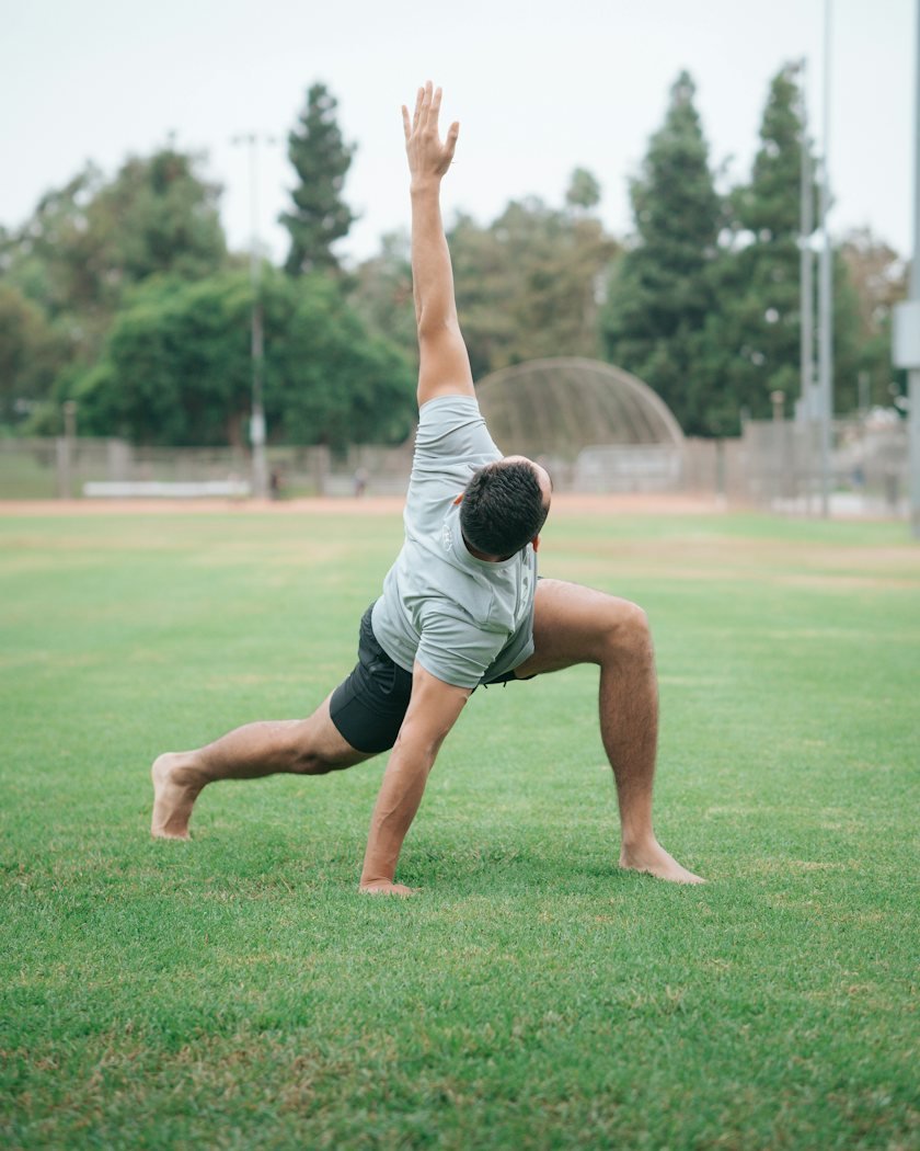 A man stretching gently on the grass in a park