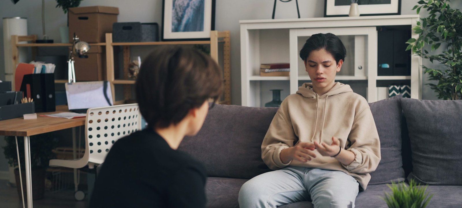 A young person sitting on a sofa, talking openly with a counsellor