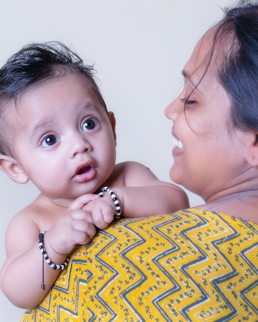 A mother smiling as she holds her baby over her shoulder